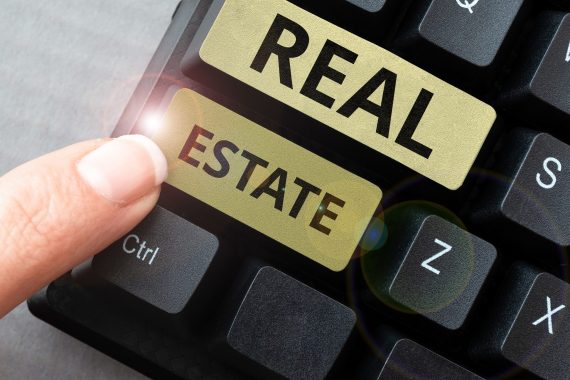 Finger presses keyboard button marked "real estate"