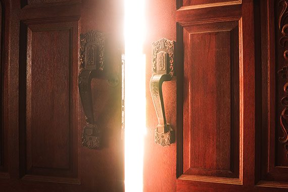 Heavy doors cracked open with bright light shining through